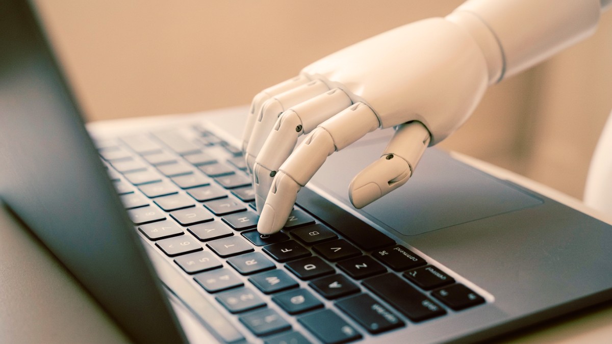 Mão robótica digitando em teclado de notebook representando o Marketing de conteúdo com IA em 2026